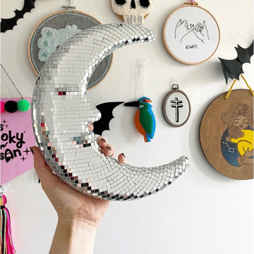 Disco moon pendant reflecting sparkles on white wall