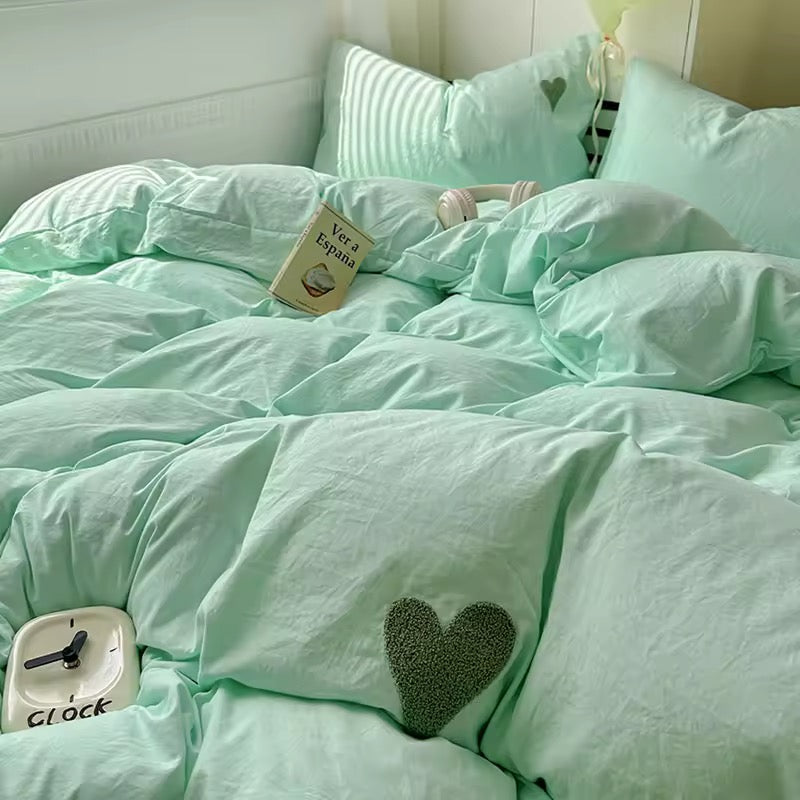 Twin bed with mint green cotton duvet and flat sheet in sunlight.