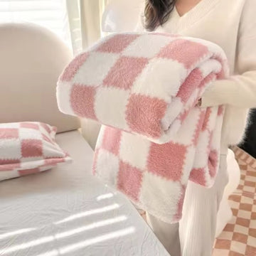 Person holding a pink and white checkered blanket in a cozy room.