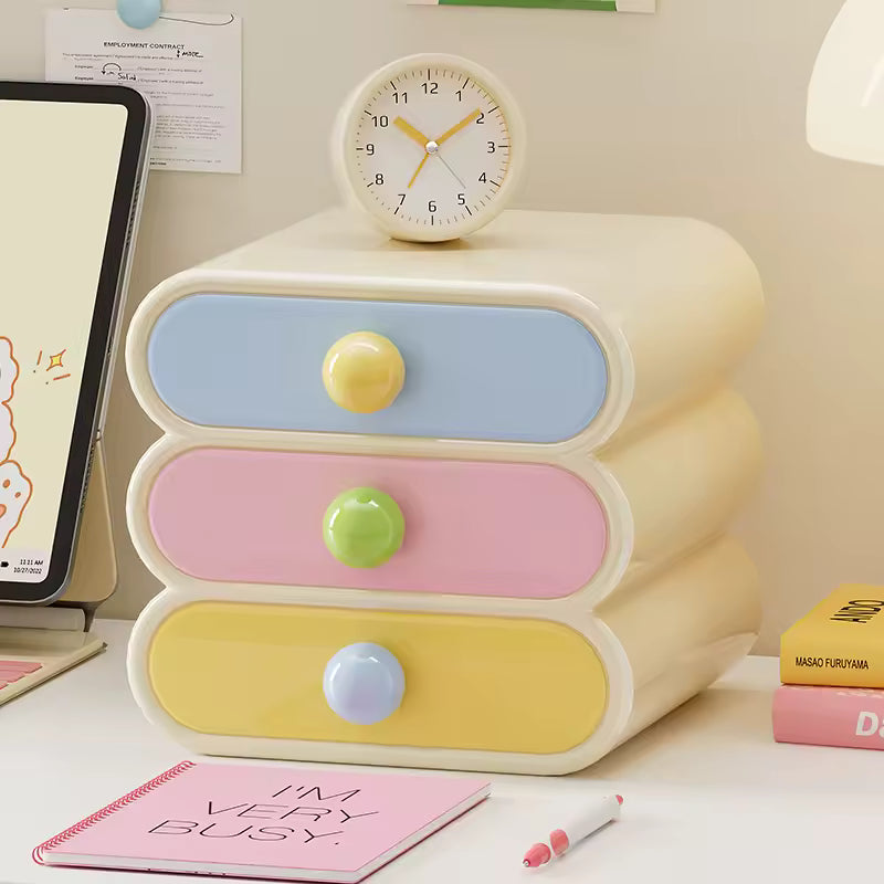 Pastel-colored three-drawer organizer with colorful knobs on a desk.
