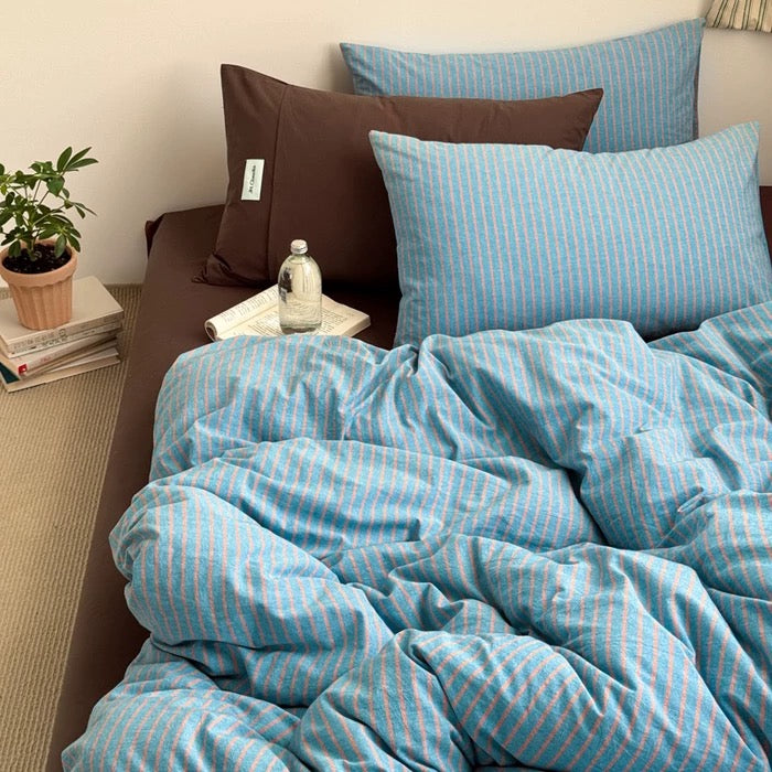 Apartment bedroom styling – blue striped duvet cover, neutral sheets, soft aesthetic.