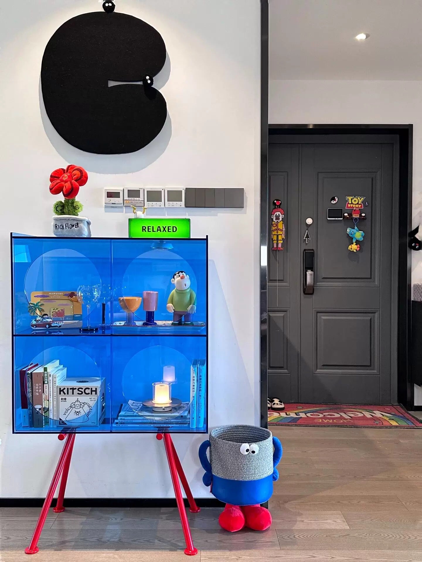 Acrylic figurine display cabinet styled with art toys books and modern decorative accents