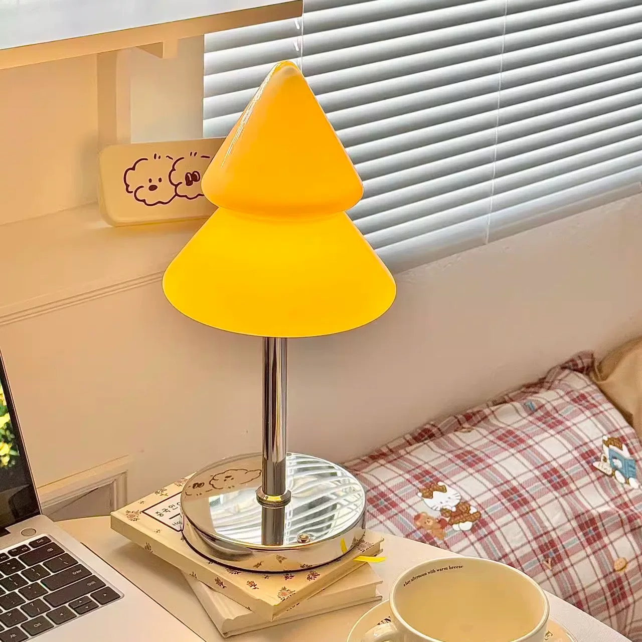 Yellow lamp on a desk with a laptop and mug in a room setting