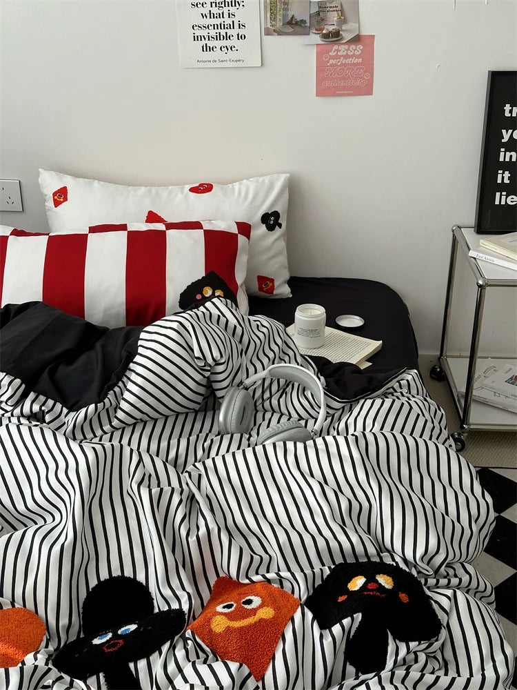 Bed with black and white striped bedding featuring cartoon characters, in a room setting.