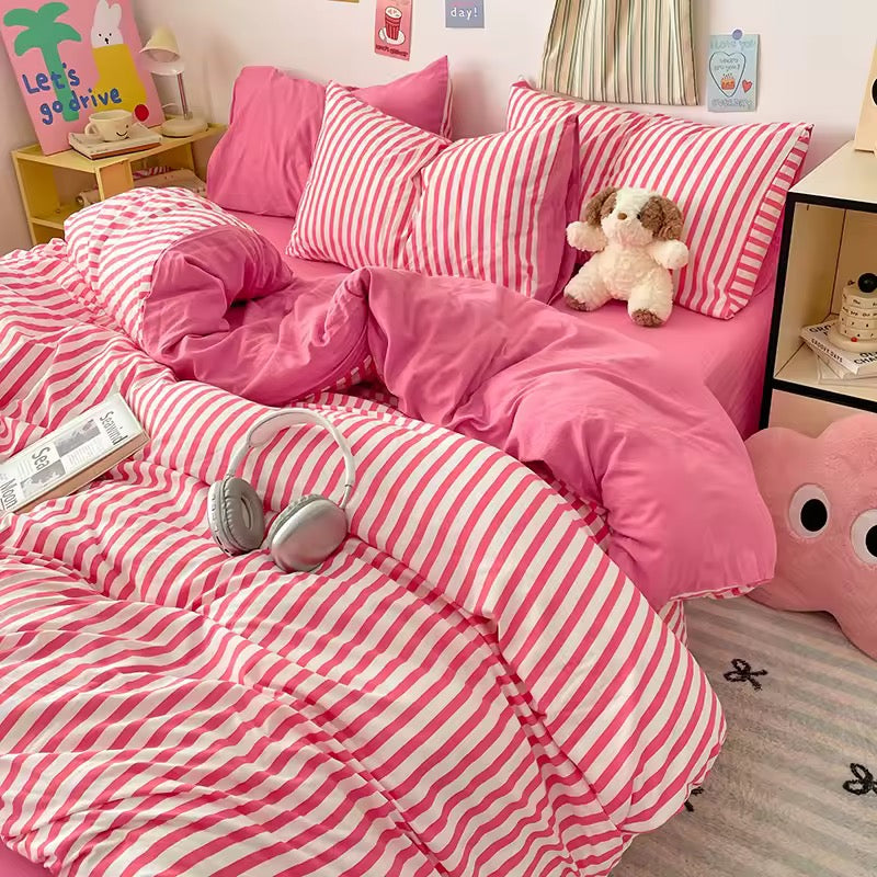 Pink and white striped bedding set on a bed in a room with decorative elements.