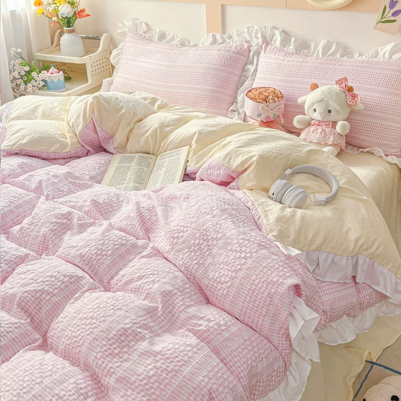 Pink and white bedding set with plush toys in a bedroom setting