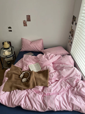 Bed with pink bedding and a brown sweater, next to a nightstand with a lamp.