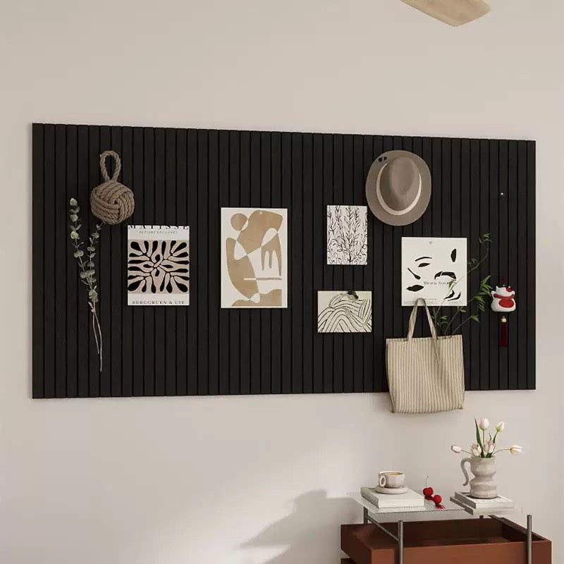 Black wall panel with decorative items including a hat, bag, and small plants on a light-colored wall.
