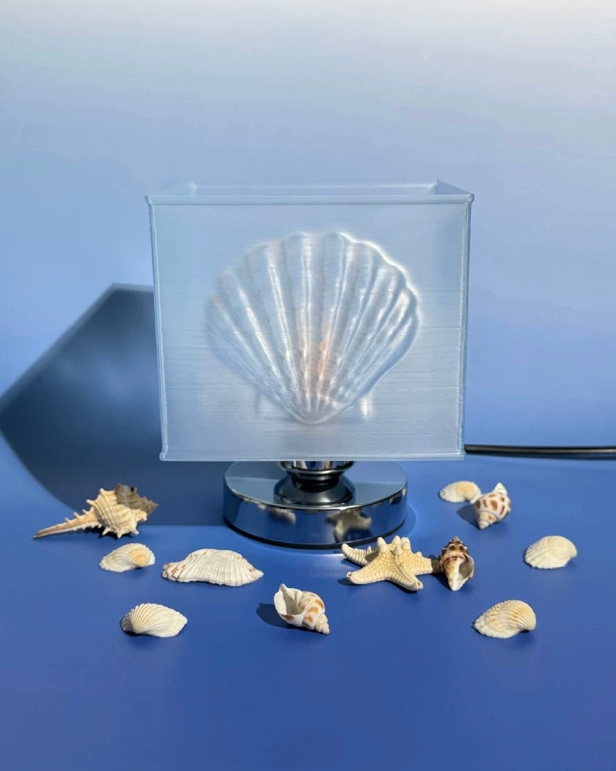 Clear silicone mold shaped like a shell on a blue background with small shells around it.