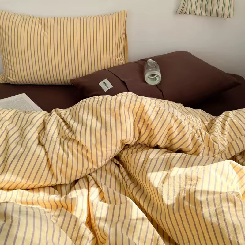 Cozy yellow stripe cotton sheets styled in soft Nordic bedroom design.