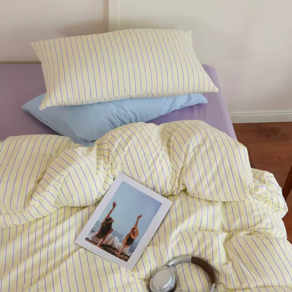 Yellow striped bedding with a photo and bottle on a bed