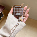 Hand holding a plaid case with a star-shaped keychain against a neutral background