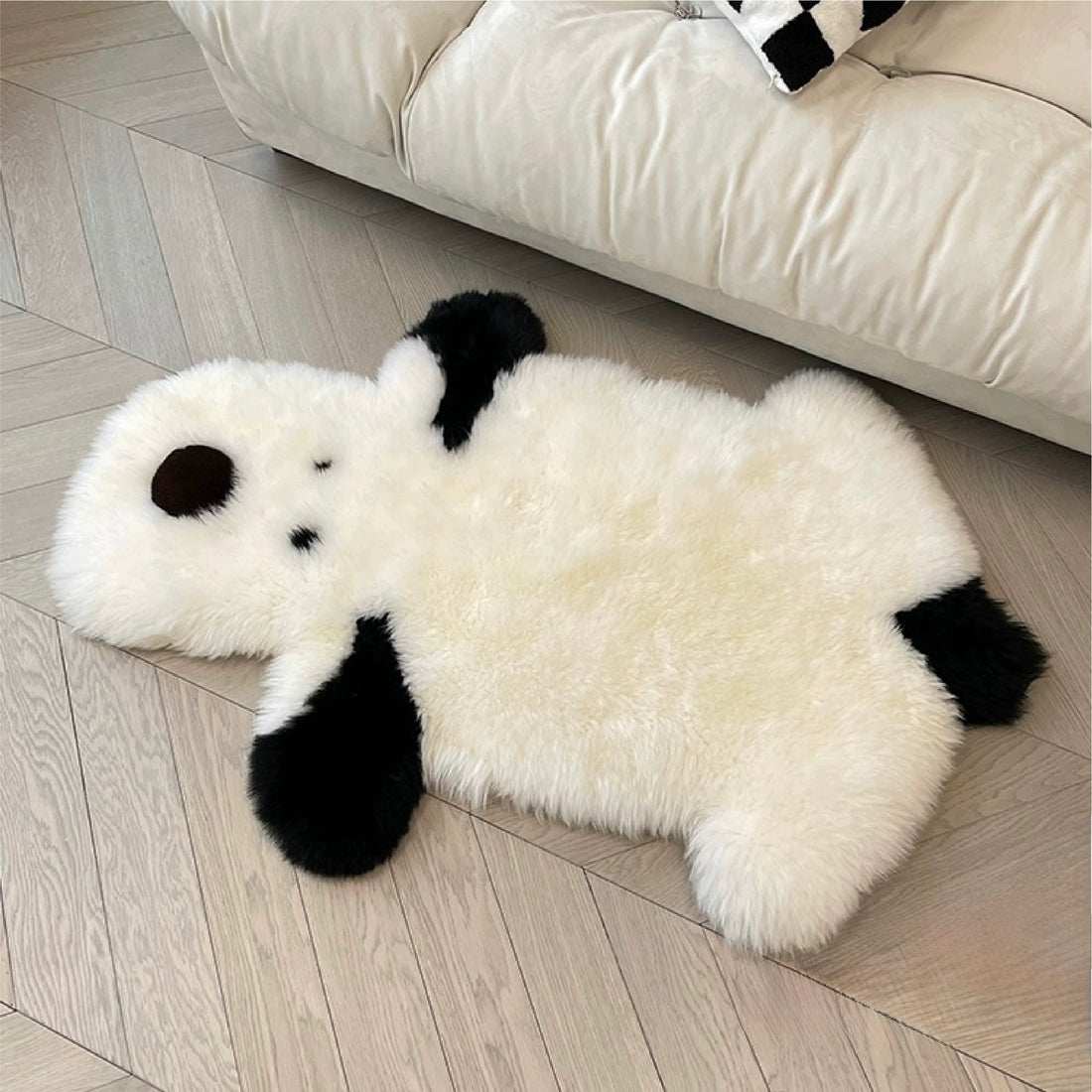 A white puppy rug rests across a chair, showing small dark eyes, a round nose and long black ears.