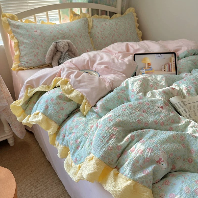 Soft girl aesthetic bed styled with floral pillowcases, pink sheets, and yellow ruffle trim


