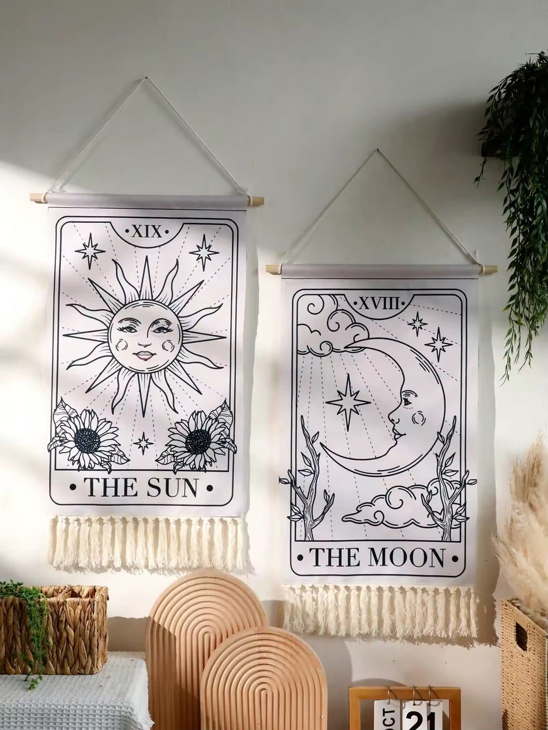 The Sun and Moon hanging side by side on a minimalist white wall with plant accents.