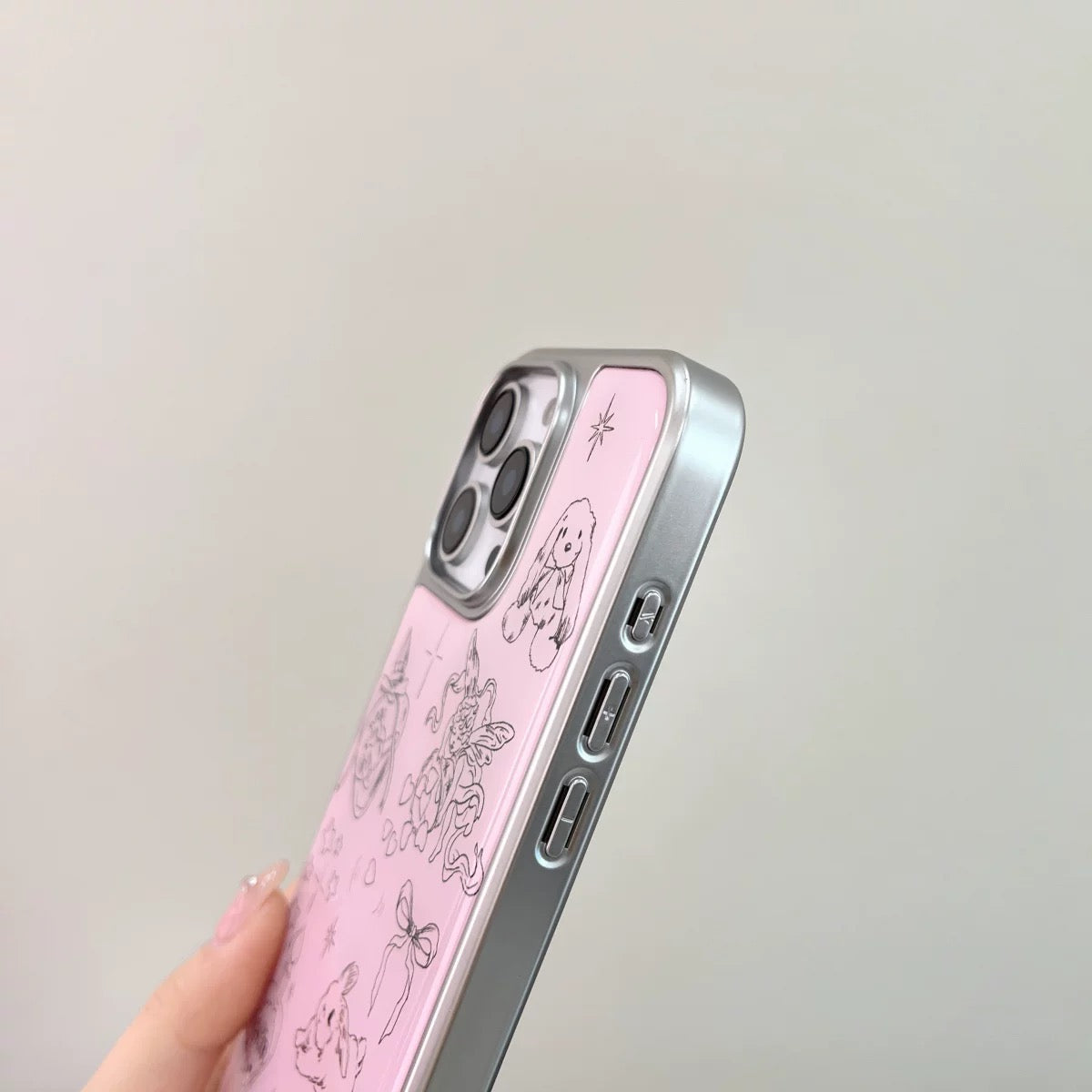 Pink phone case with floral design held by a hand against a light gray background
