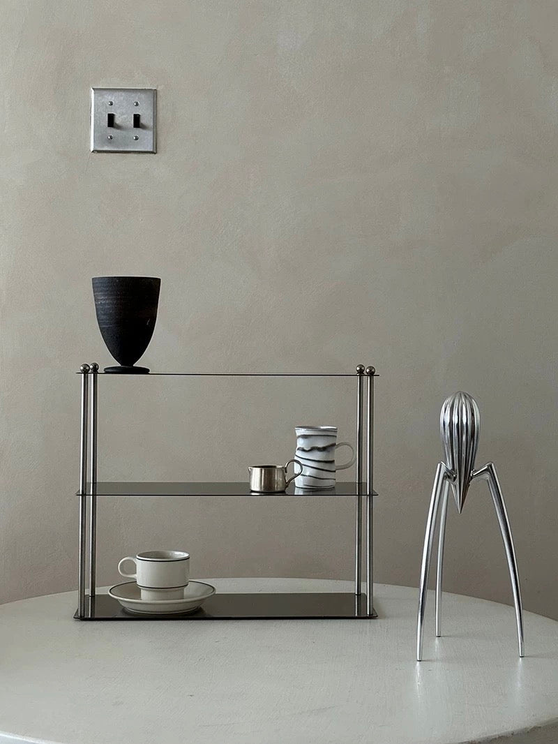 Modern glass shelf with decorative items against a plain wall.