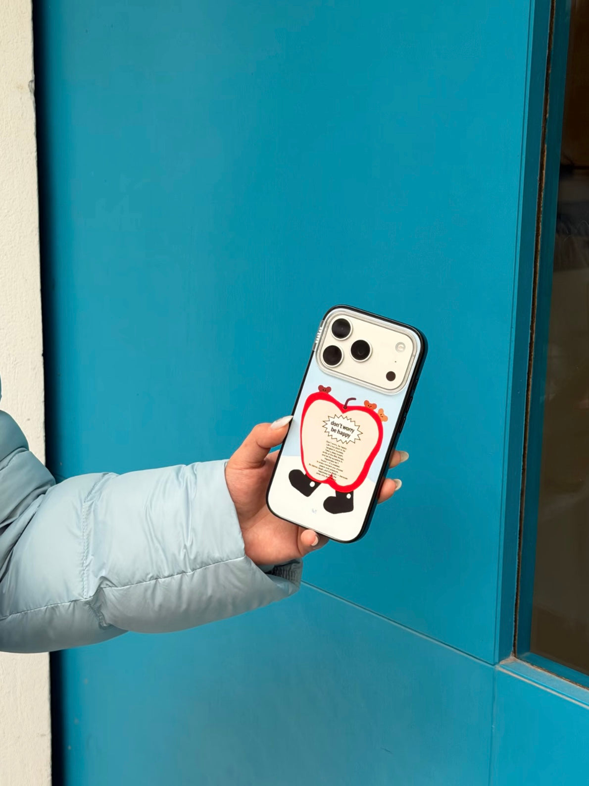 A bear apple phone case is held upright against a blue background, with the red apple covering most of the back.