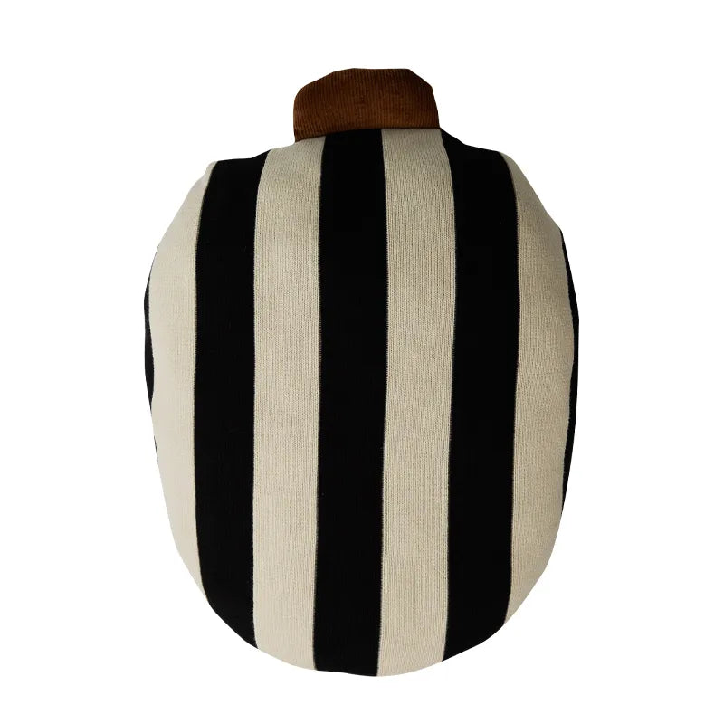 A round knit cushion cover featuring bold vertical black and cream stripes, with a small brown fabric loop at the top, shown against a plain white background.