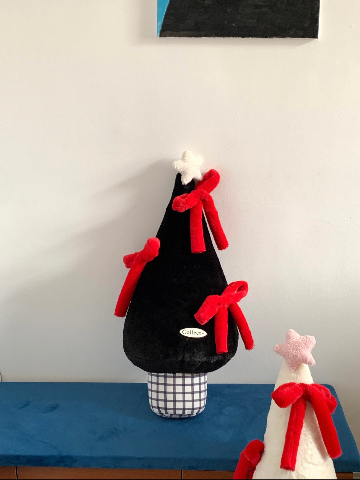 Black and red Christmas plush pillow shaped like a tree on a blue bench