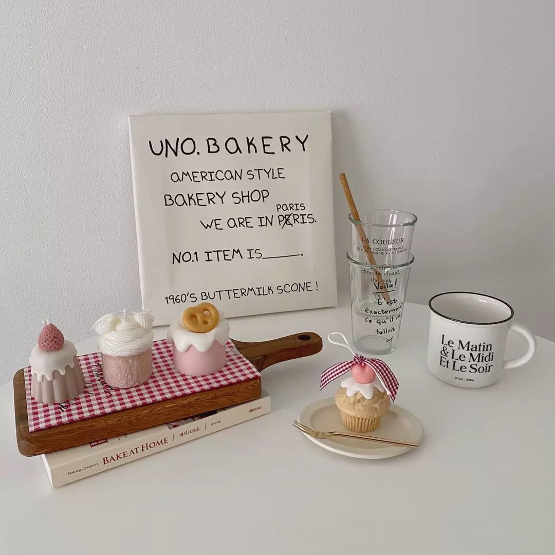 A styled tabletop arrangement featuring a white sign reading 'UNO. BAKERY AMERICAN STYLE BAKERY SHOP PARIS WE ARE IN PARIS NO.