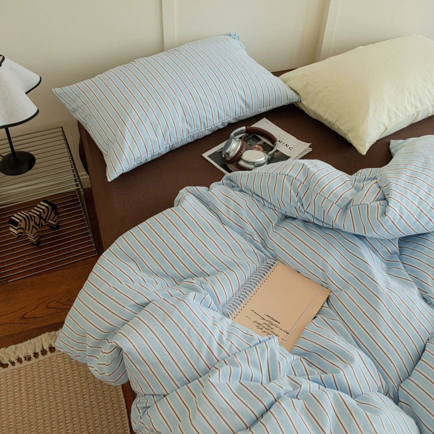 Striped bedding set on a bed with pillows and a lamp in the background