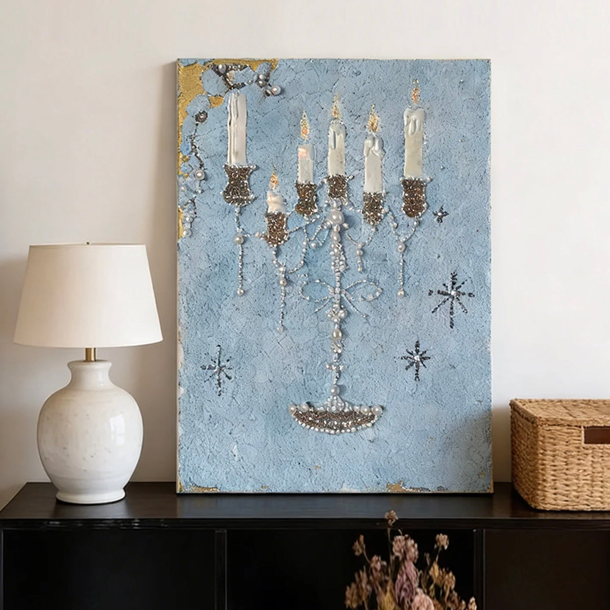 Blue candle canvas art above a dark console beside a white table lamp