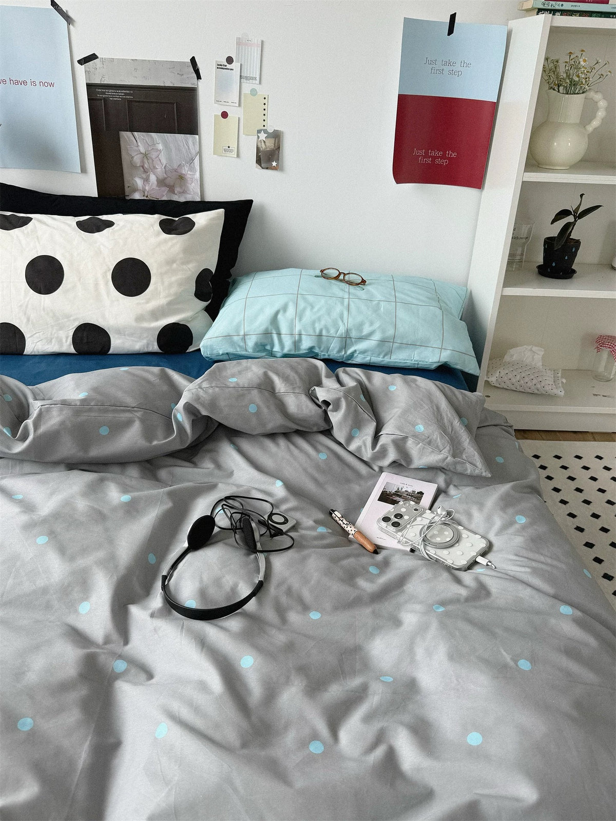 Blue check and black dot pillowcases arranged above the gray duvet cover.