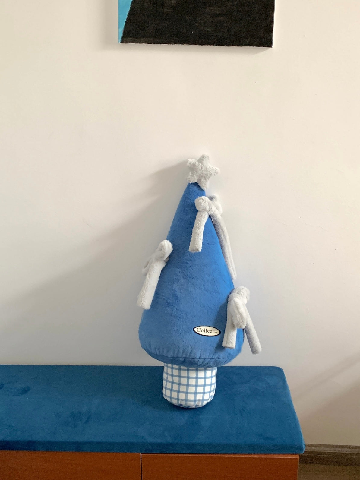 Blue Christmas tree shaped pillow with white bows styled on a bench