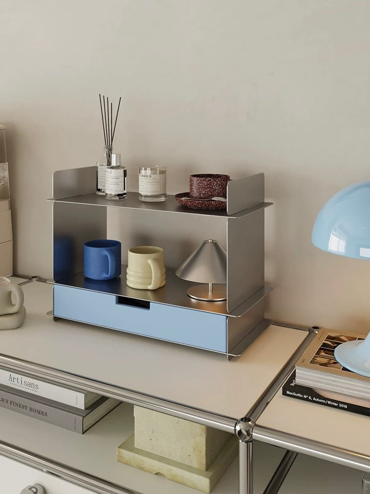 Blue desk shelf with a drawer on a chrome frame table beside a blue lamp