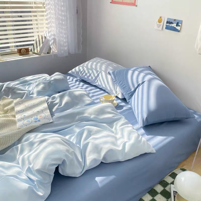 Blue bedding set with duvet cover and pillowcases styled in a cozy minimalist bedroom.