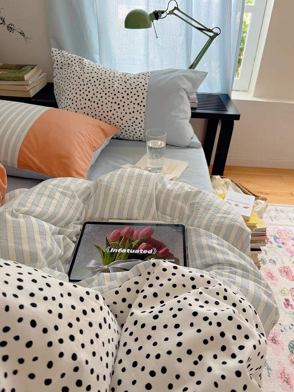 Blue and yellow striped bedding is folded beside a bright window, with dotted fabric in the foreground.