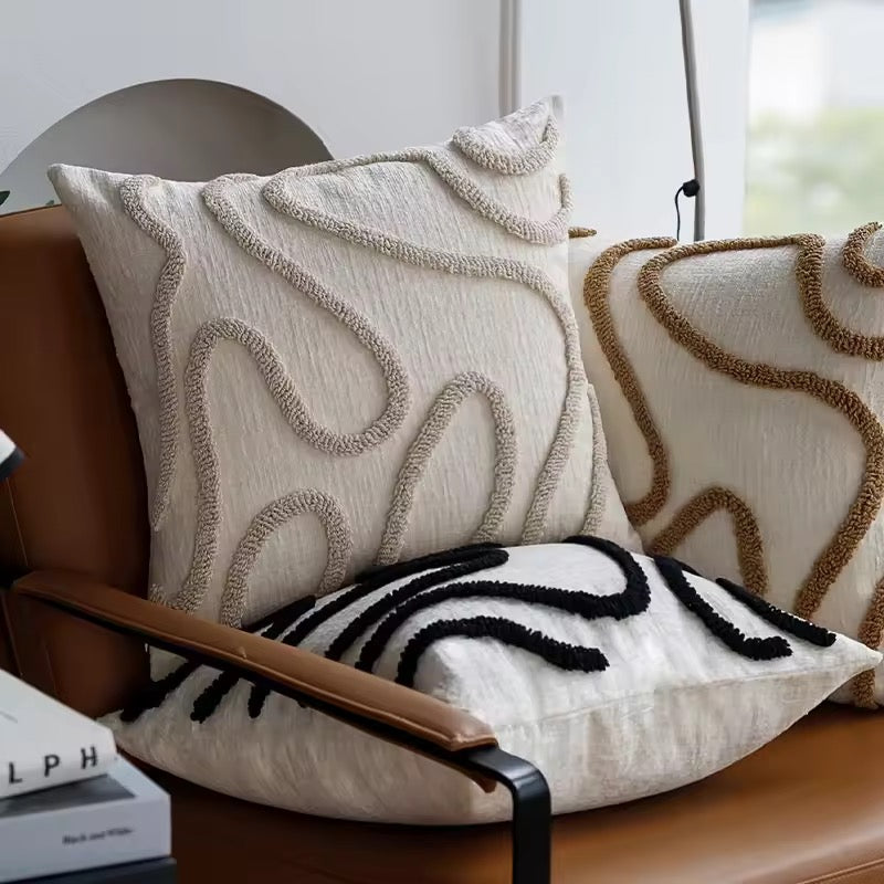 Decorative pillows with textured patterns on a brown chair.