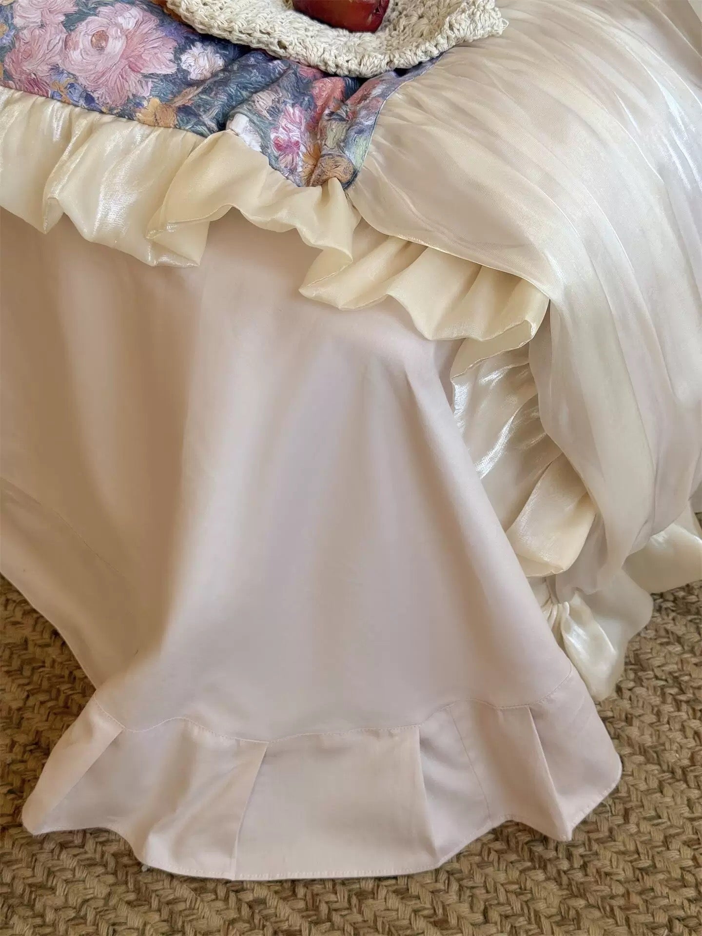 Close-up of a white satin skirt with ruffles on a textured surface.