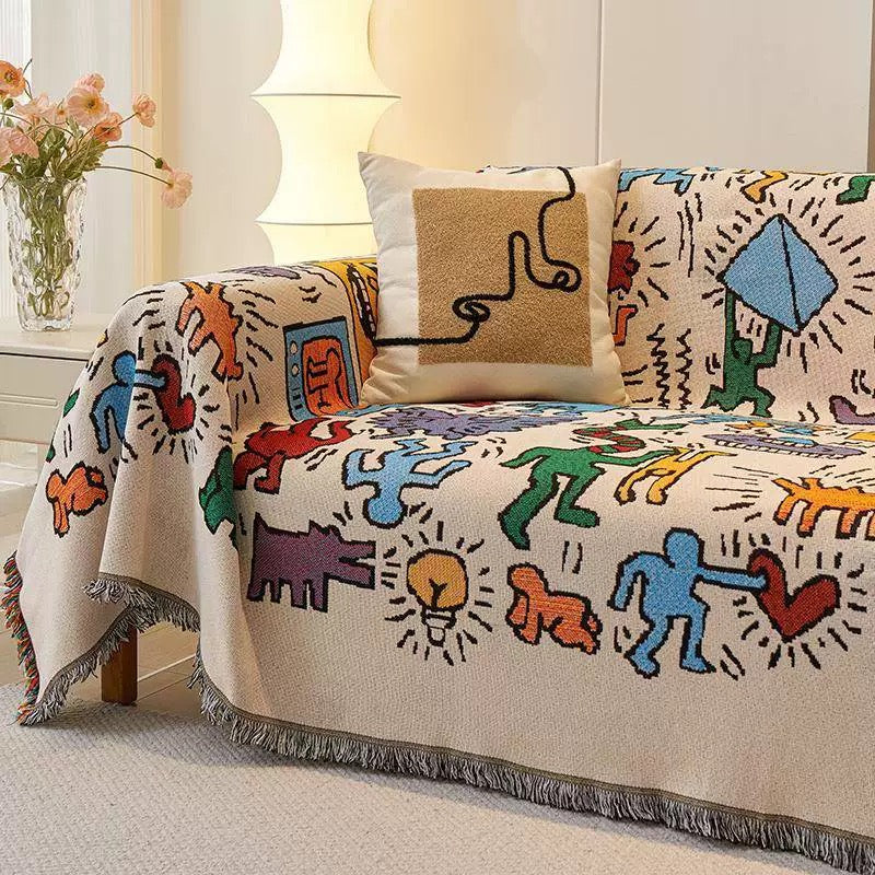 Colorful jacquard throw blanket with retro figures draped over a couch in a boho-style living room