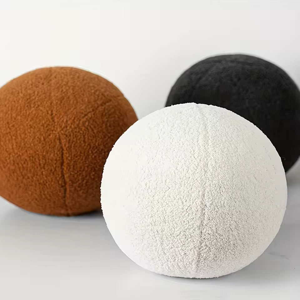 Three textured balls in brown, black, and white on a light gray background