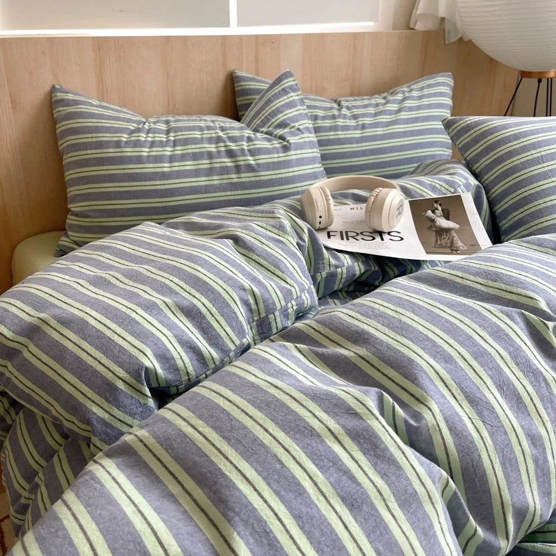 Striped bedding set on a bed with pillows and a magazine.