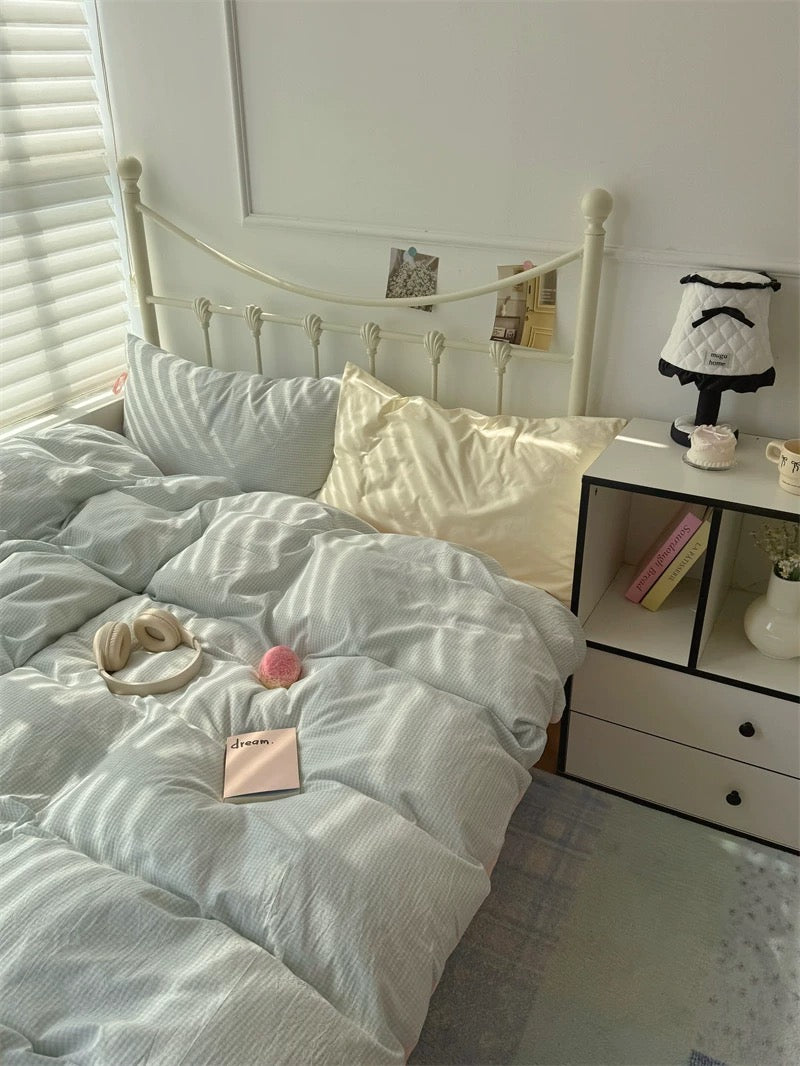 Bed with light blue comforter and decorative items in a bedroom setting.