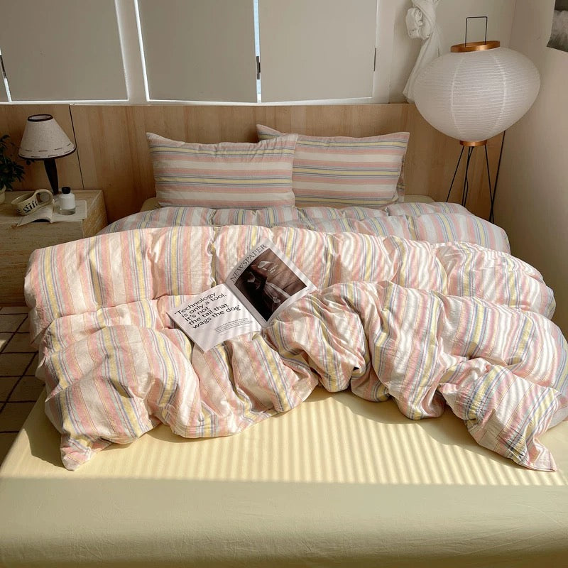 Bed with striped bedding and pillows in a well-lit room.
