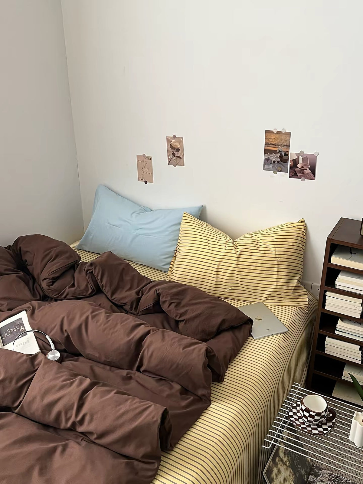 Brown bedding set with dark brown duvet and striped sheet in a small bedroom