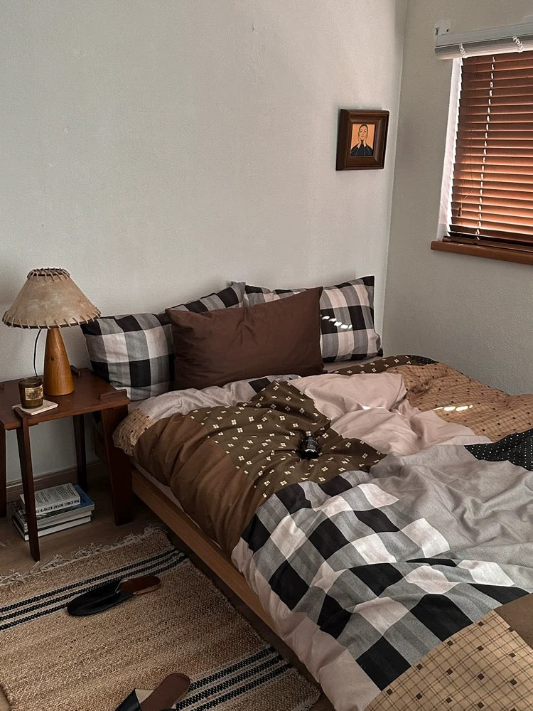Brown checkered bedding photographed beside a wooden nightstand and lamp