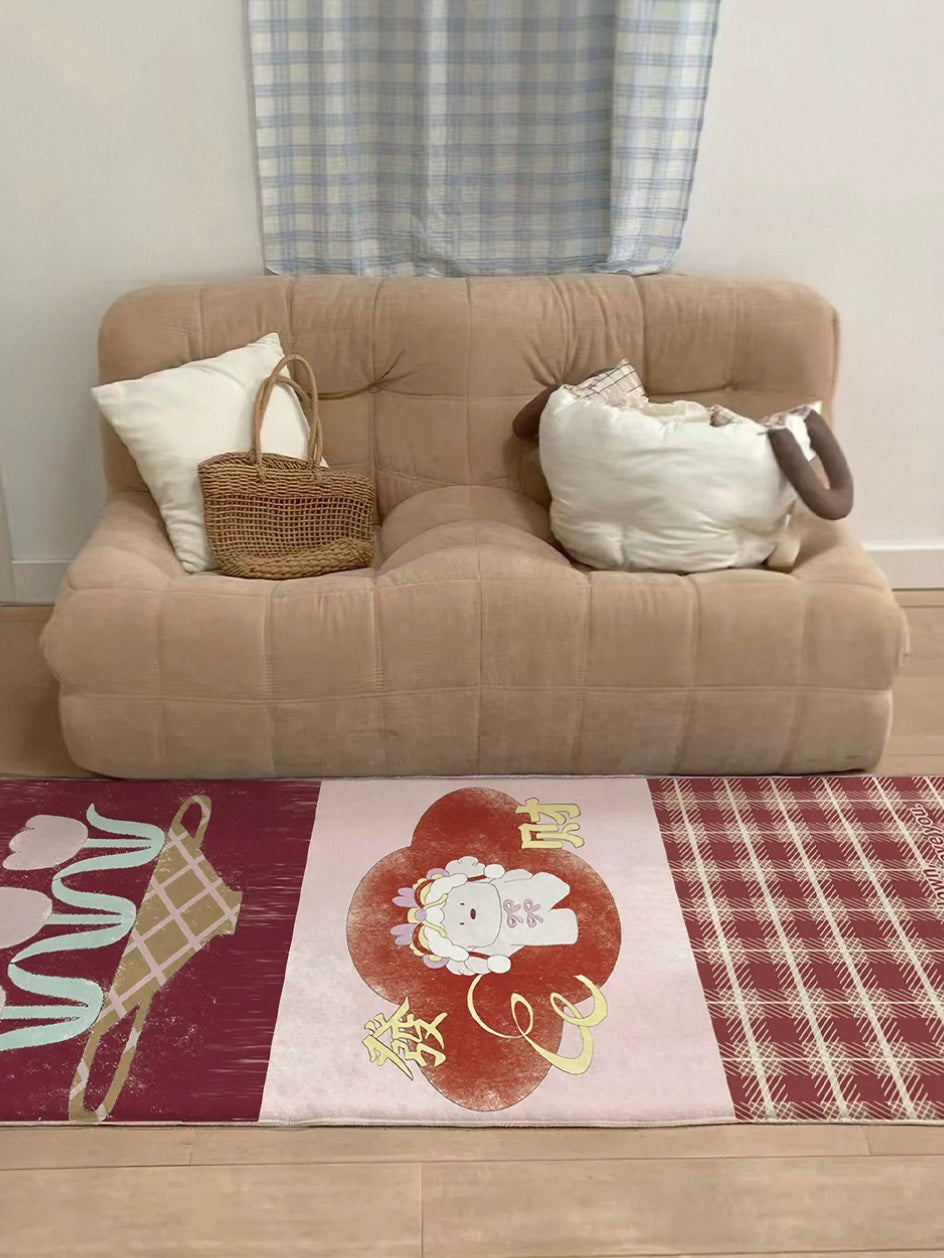 A burgundy cartoon rug lies in front of a tan sofa, with tulips and checked panels arranged across it.