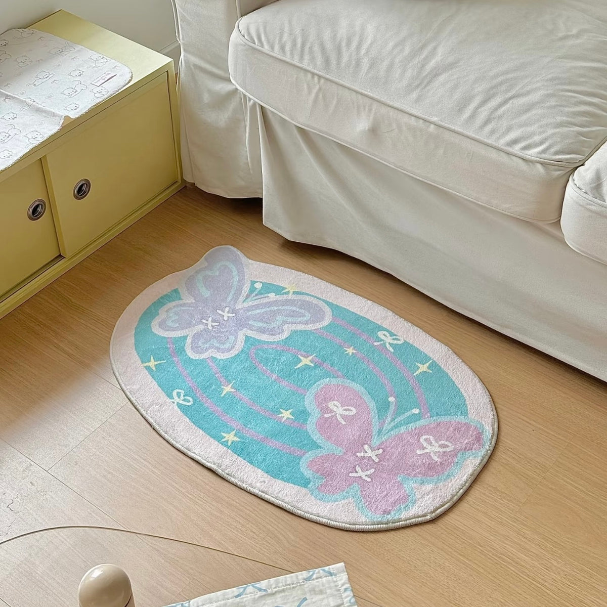 Pastel butterfly bath mat beside a white sofa on warm wood flooring