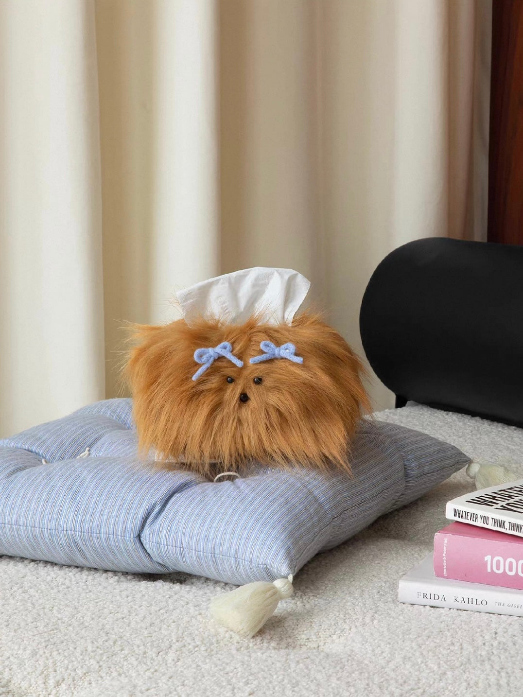 Caramel tissue cover with blue bows rests on a blue cushion, with a tissue emerging from the top opening.