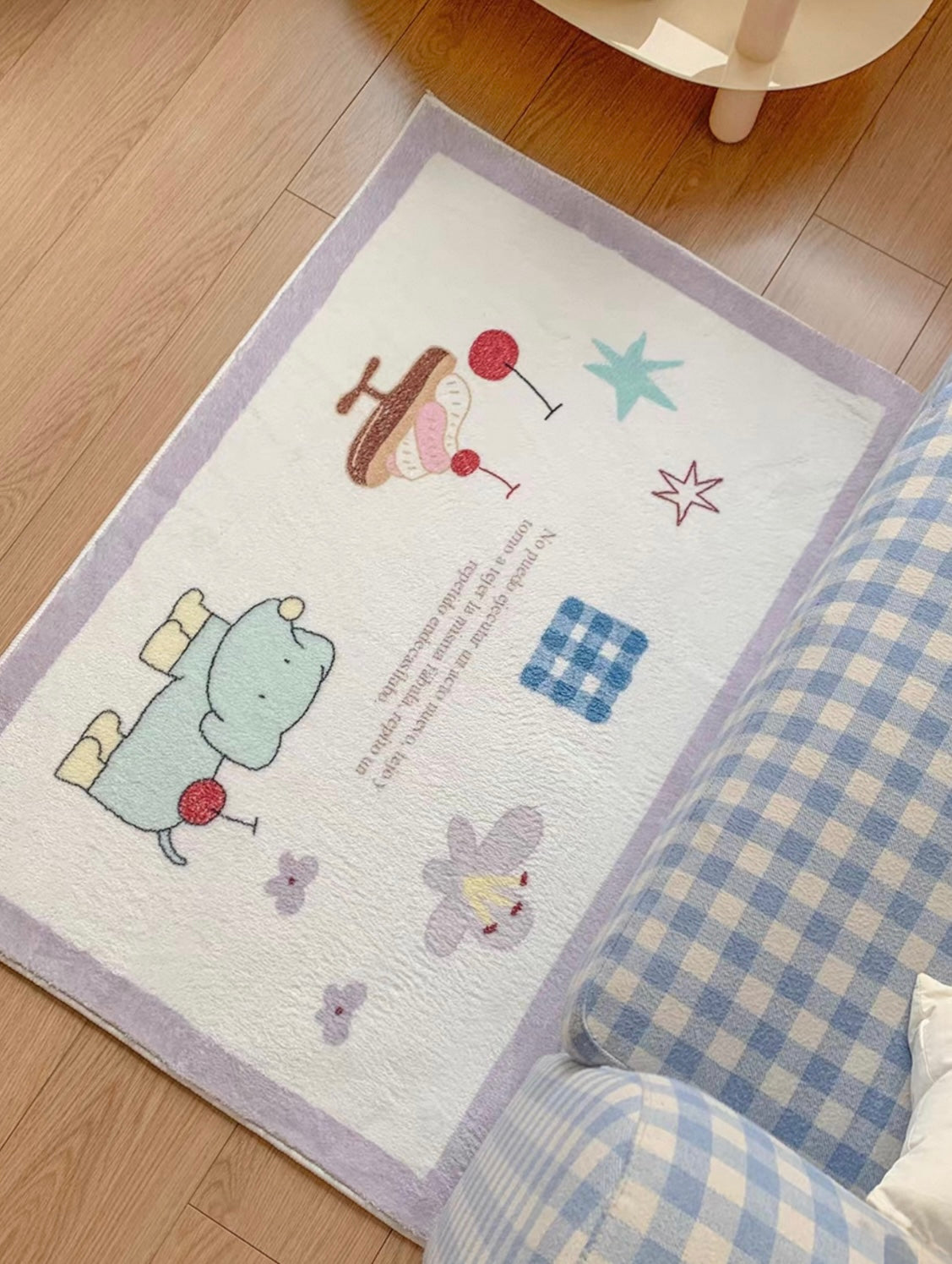 A cartoon animal rug with a purple border shows a green character and cherry artwork beside a checked armchair.