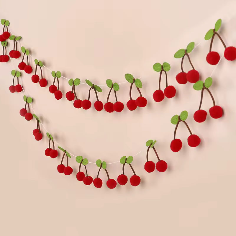 Decorative garland made of red cherries and green leaves on a beige background
