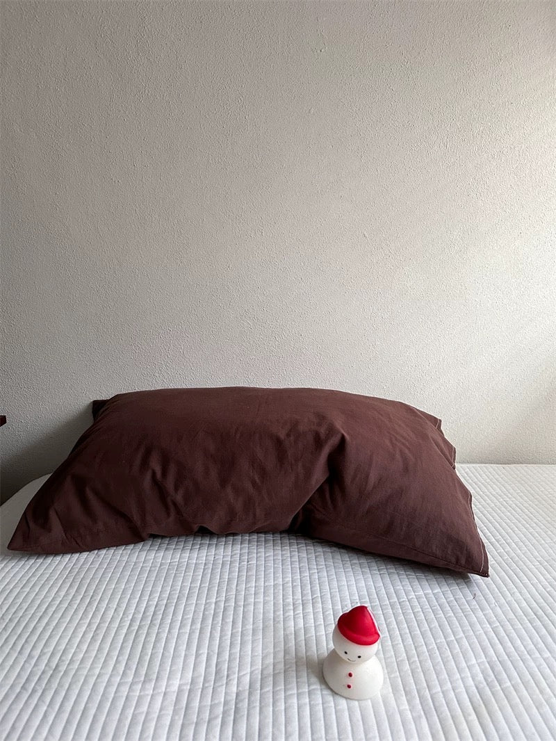 A chocolate brown pillowcase has a solid color and visible folds.
