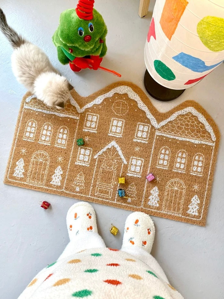 Gingerbread house Christmas door mat styled with colorful holiday decor