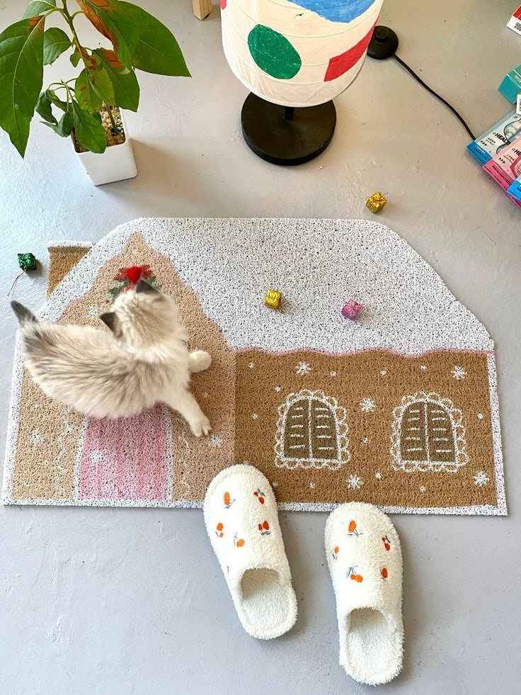 Cream Christmas entryway mat with gingerbread house design and white slippers