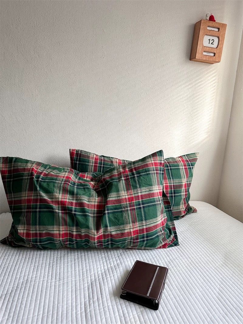 Two tartan pillowcases are arranged side by side with their red and cream lines visible.